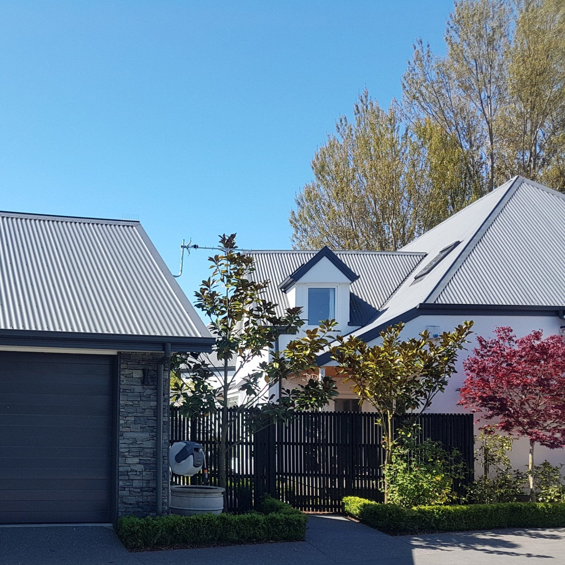 A white house with a gray roof and a black garage door