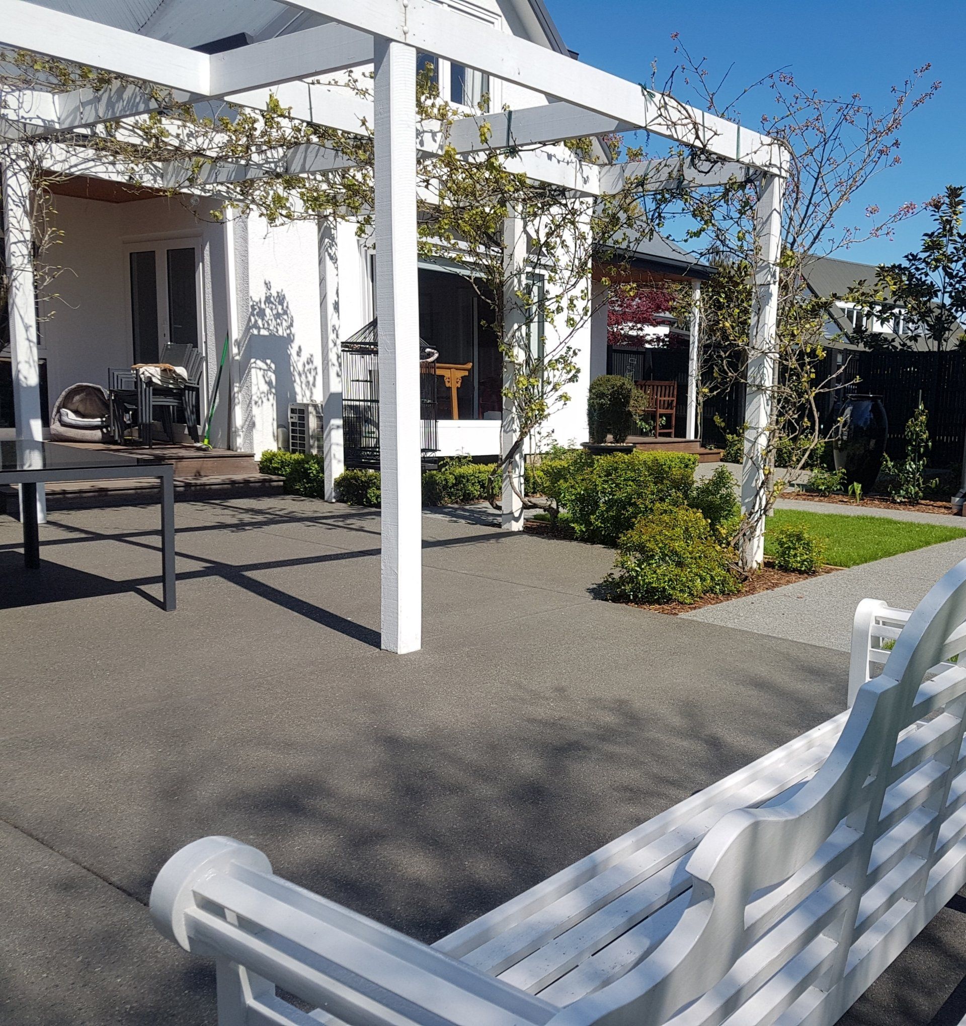 A white bench sits in front of a white house