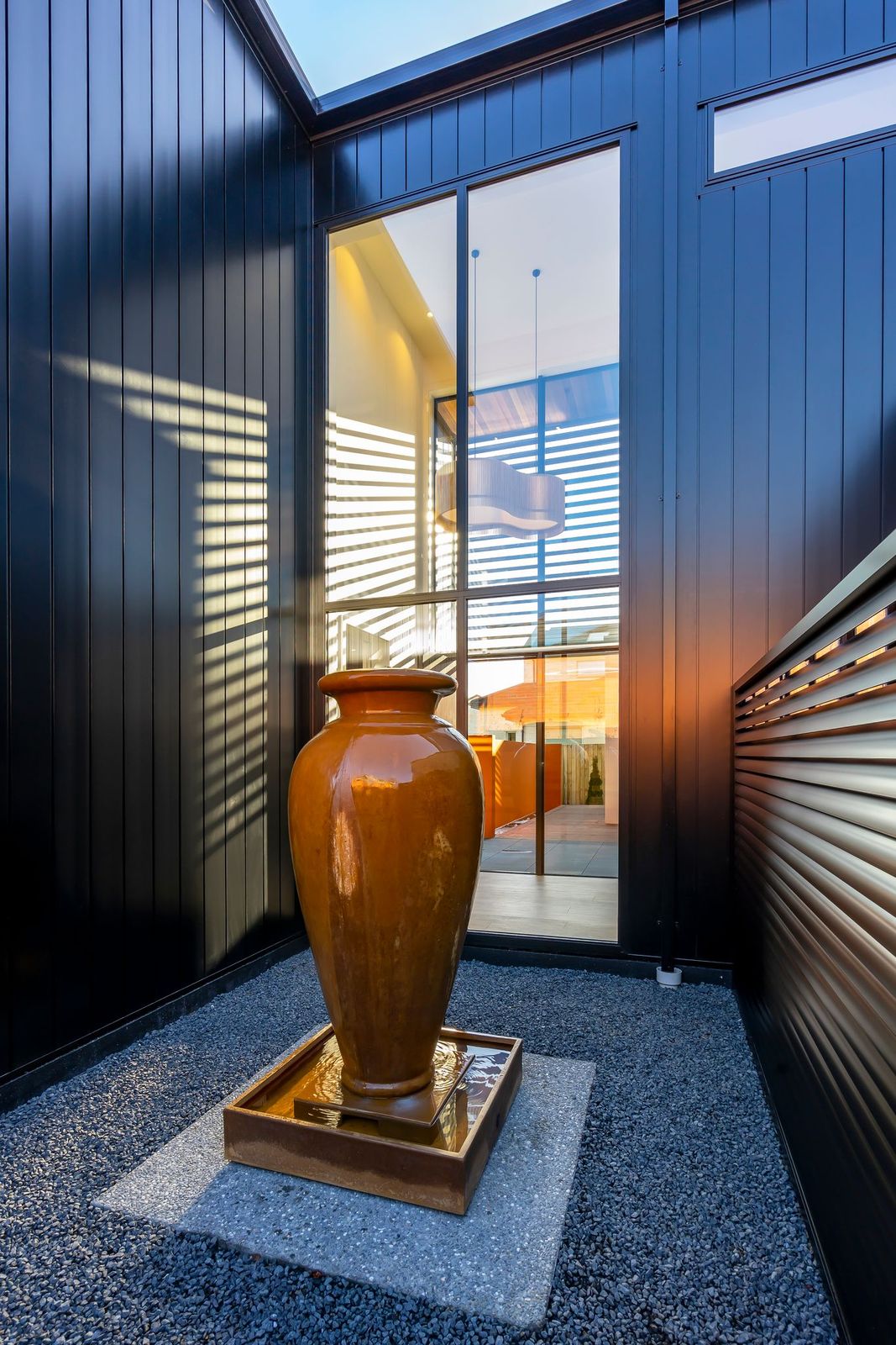 A large vase sits in front of a black building