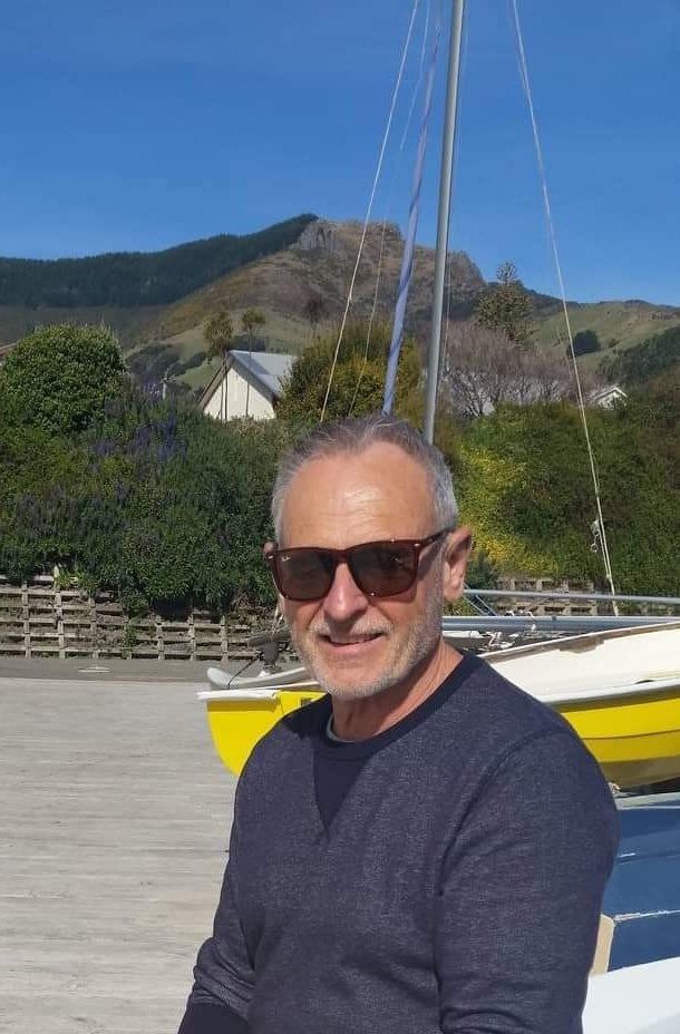 A man wearing sunglasses is sitting in front of a boat.