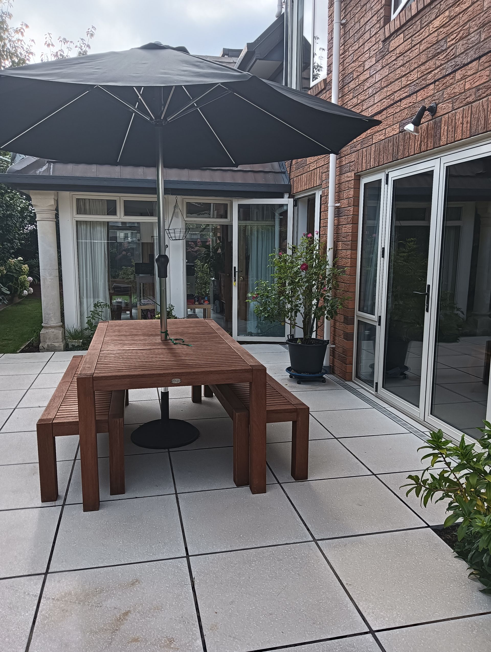 A patio with a table and benches under an umbrella