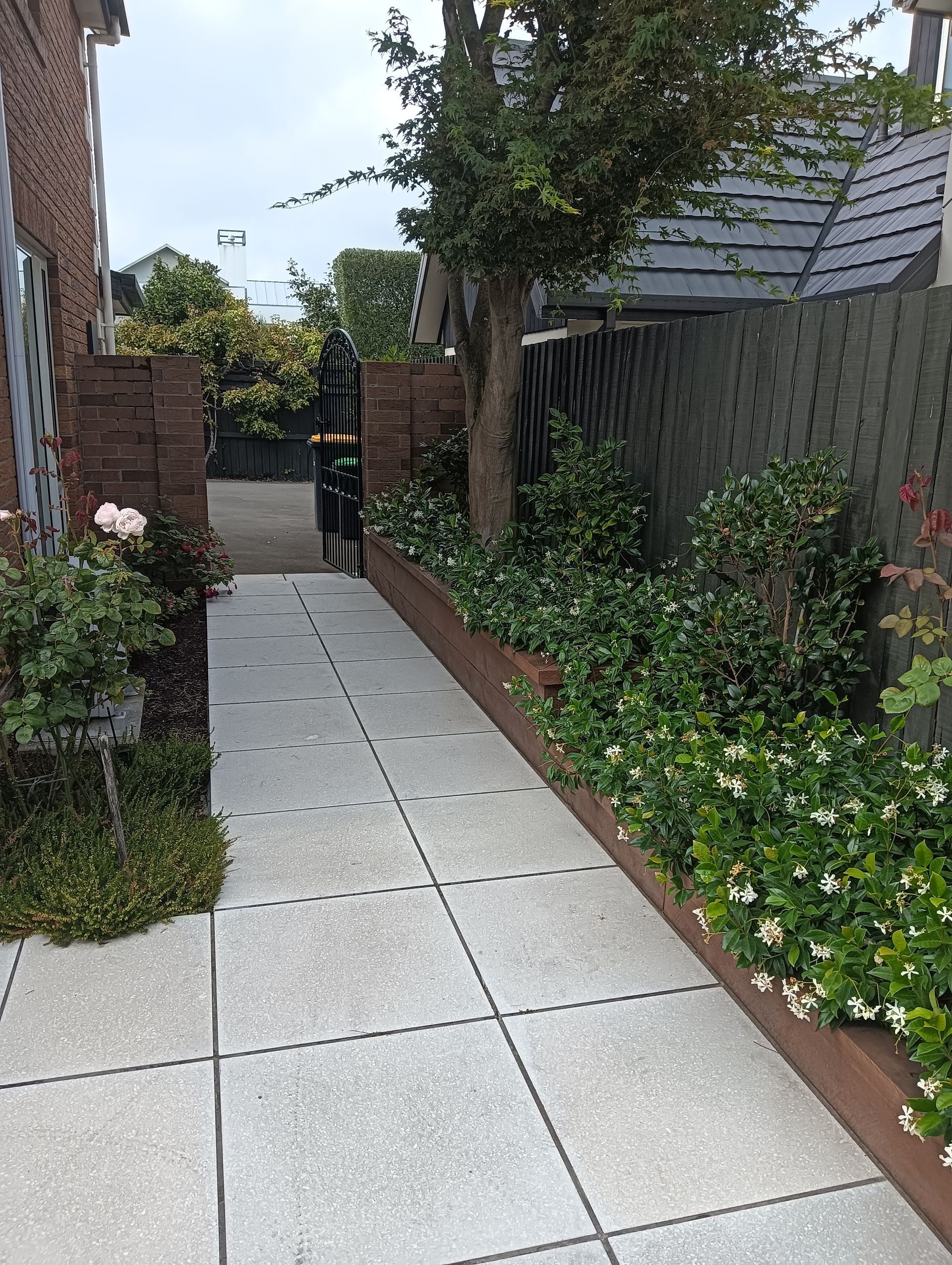 A walkway leading to a house with flowers on the side