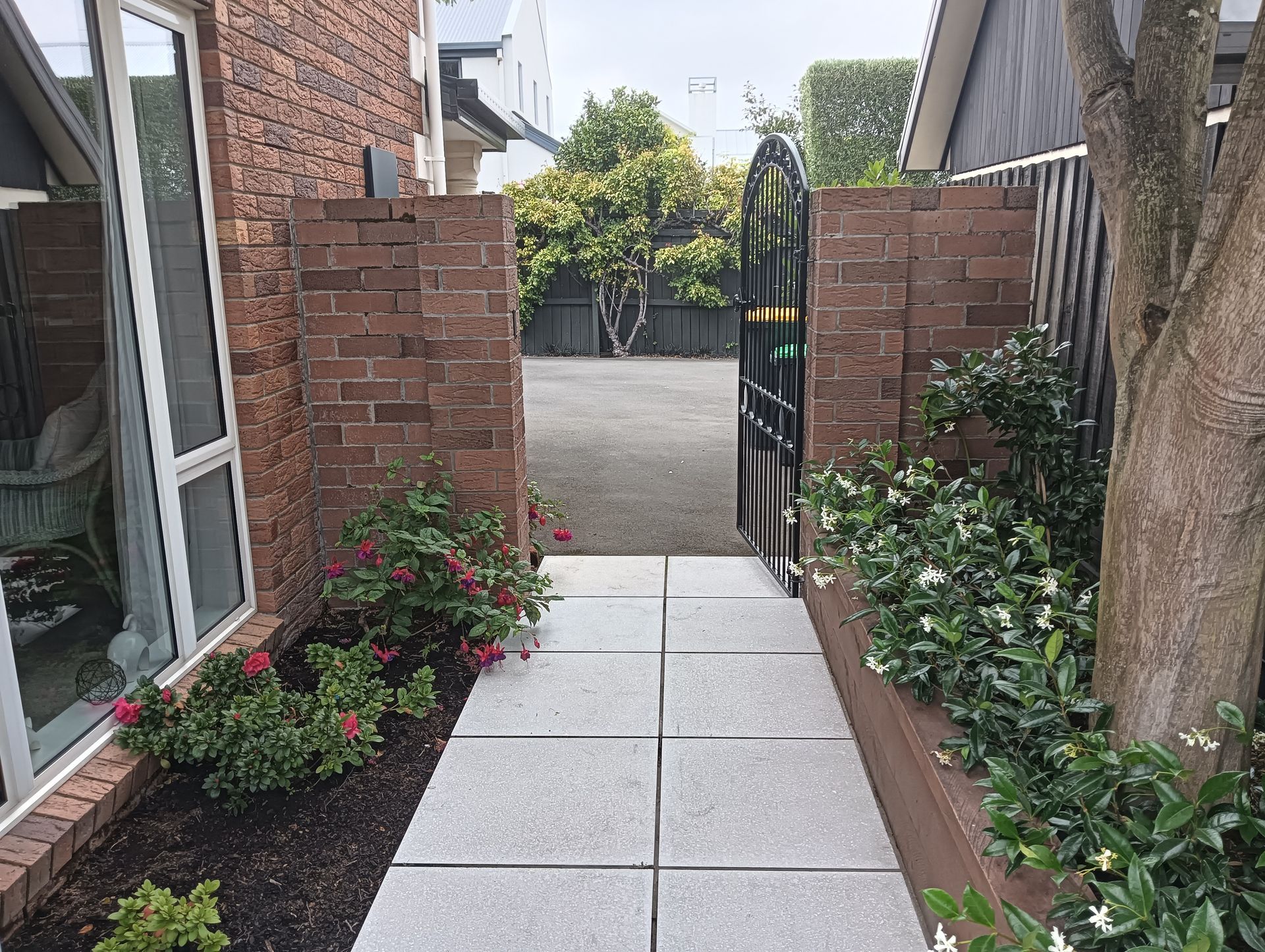 A walkway leading to a house with a brick wall and a gate