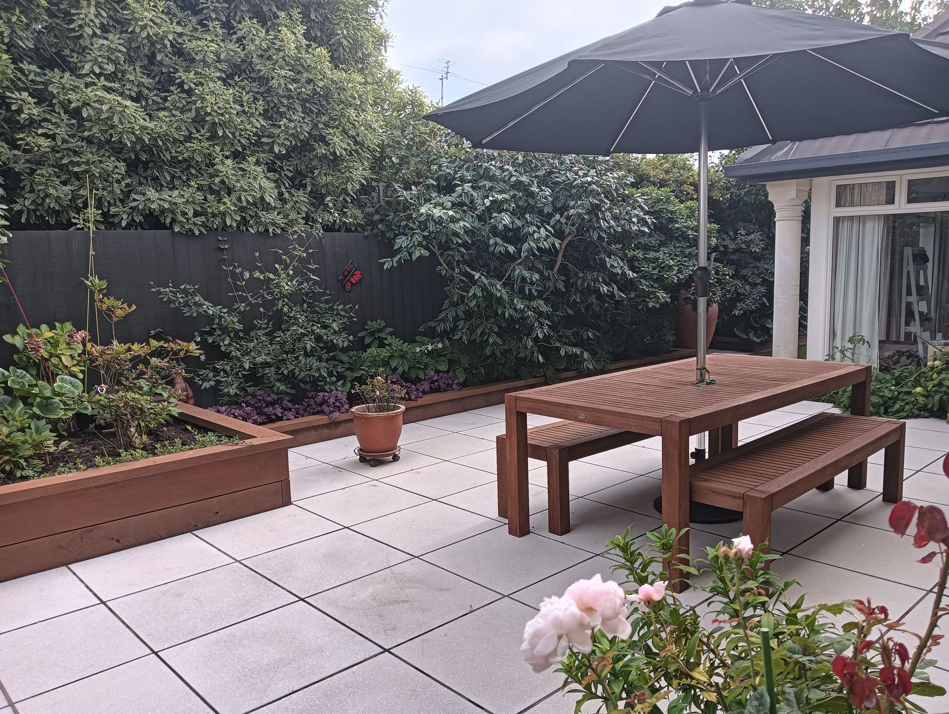 A patio with a table and benches under an umbrella