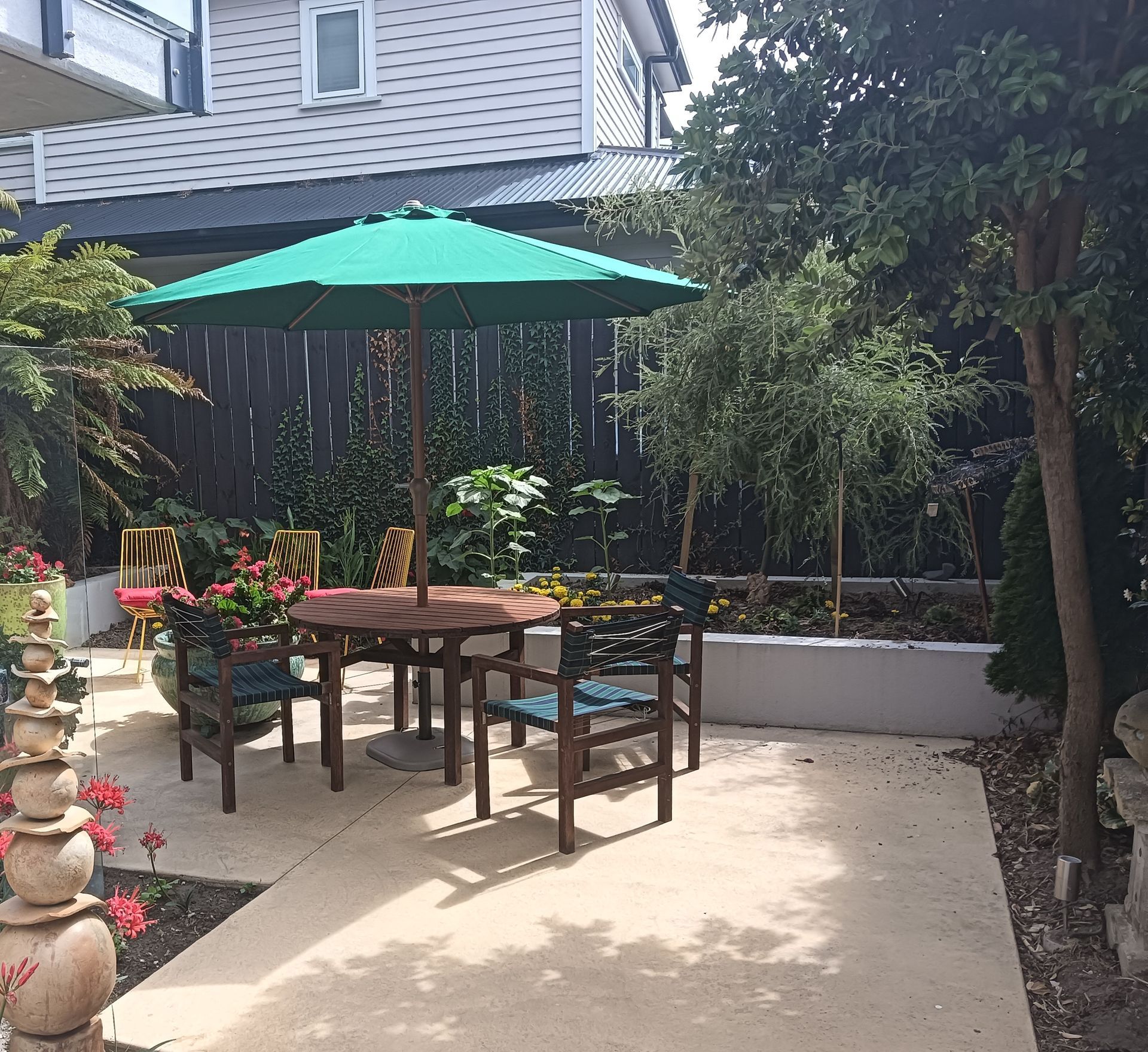 A patio with a table and chairs under a green umbrella