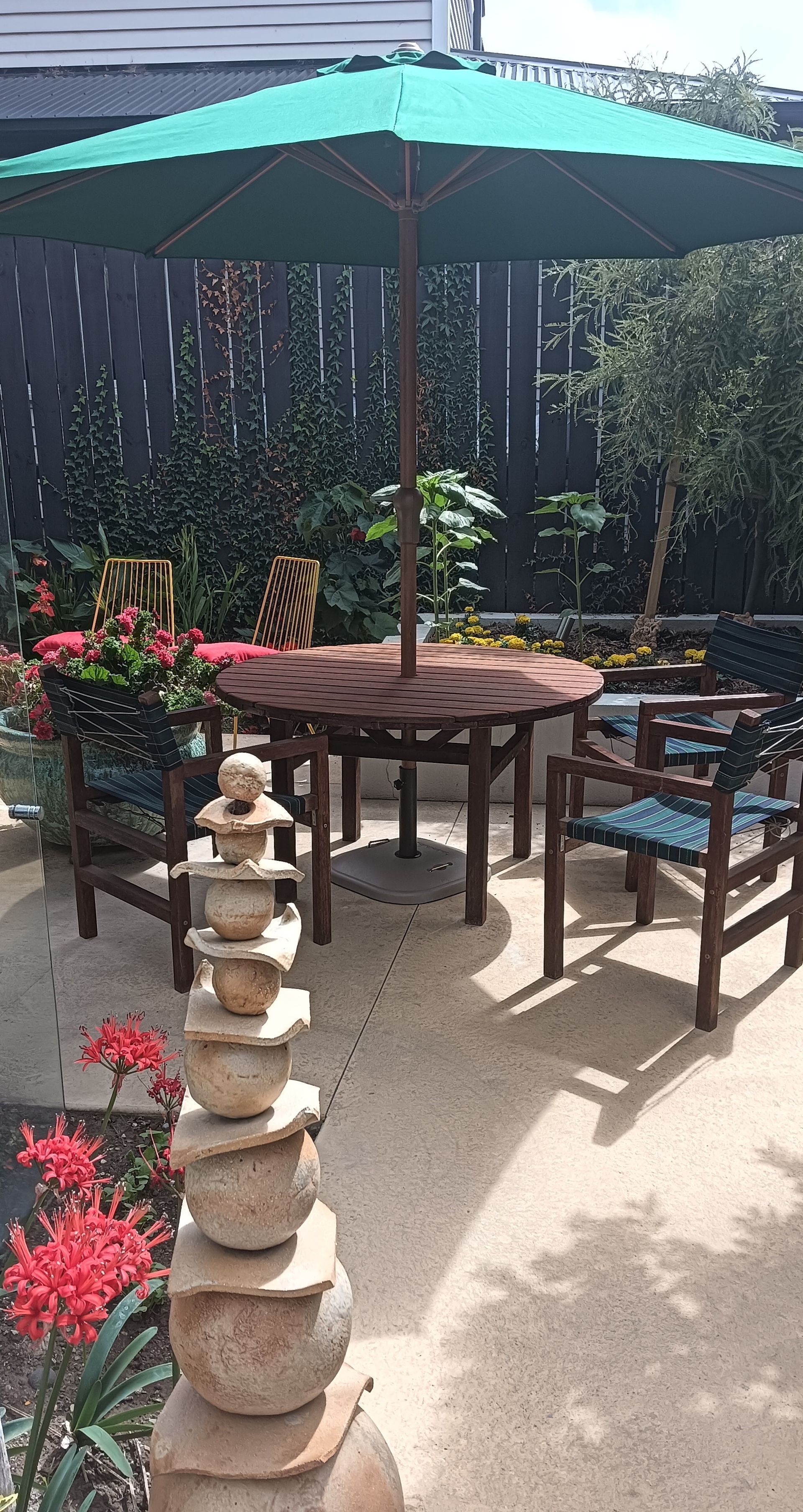 A green umbrella is sitting on top of a patio with a table and chairs.