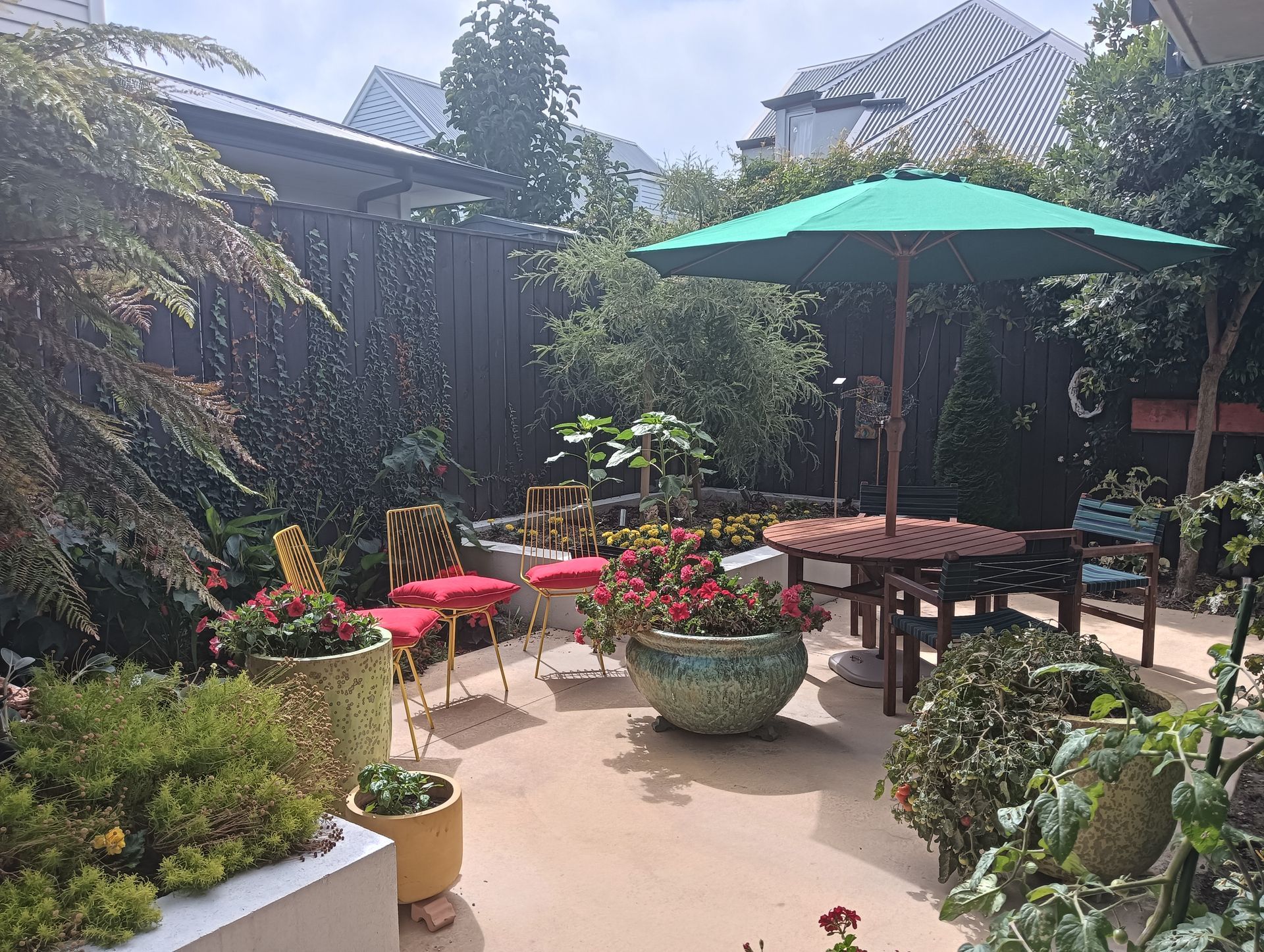 A green umbrella sits in the middle of a garden