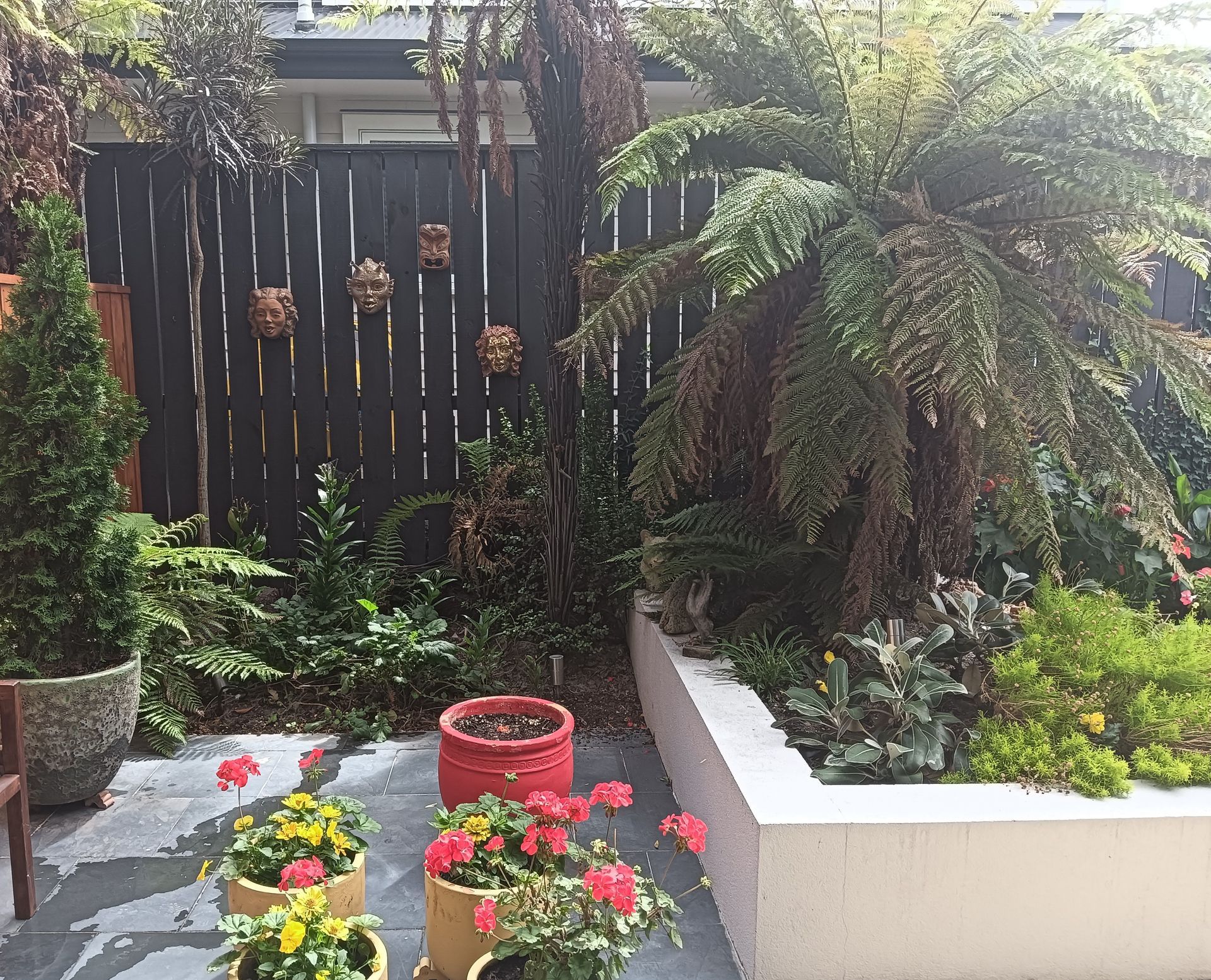 A garden with potted plants and a black fence