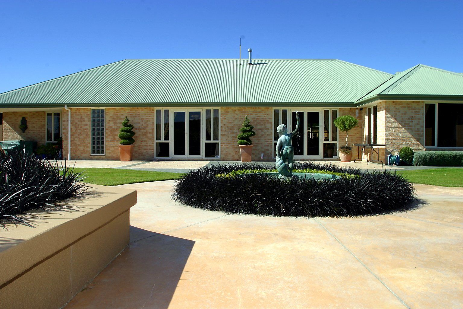 A large house with a green roof and a fountain in front of it