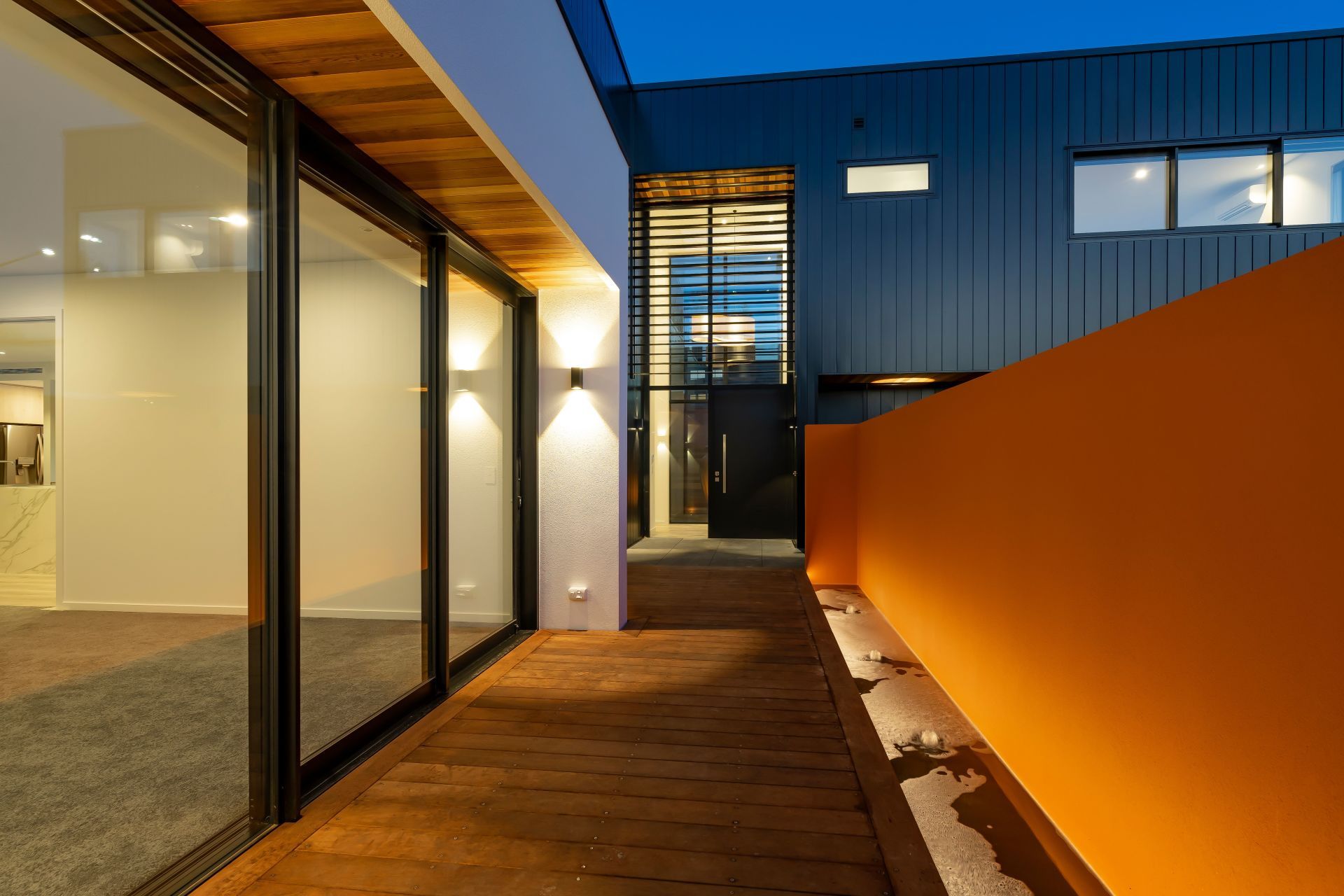 A walkway leading to a house with a large orange wall