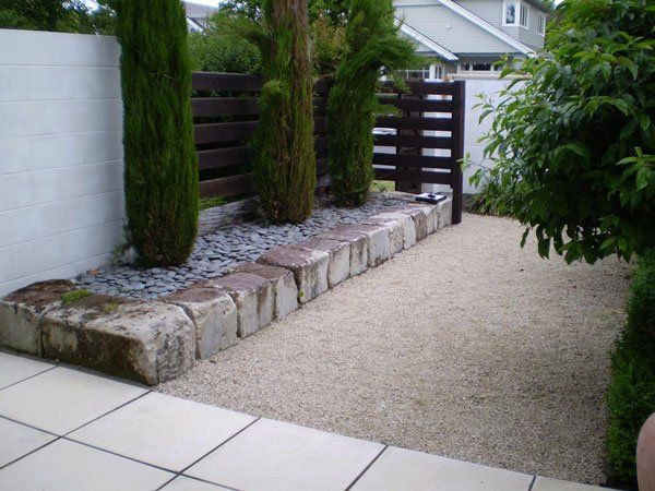 A garden with rocks and gravel and a wooden fence