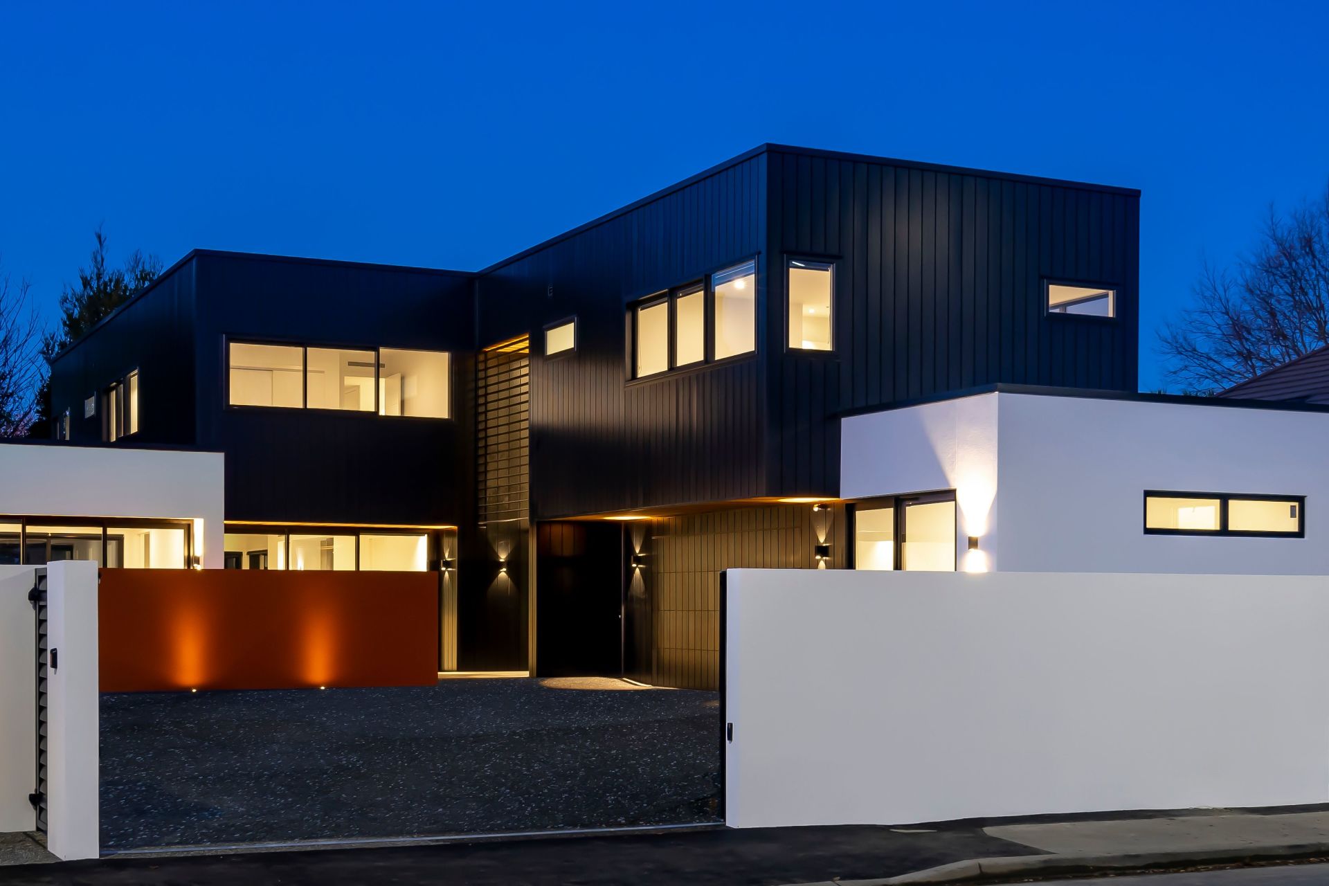 A large black and white house with lots of windows is lit up at night