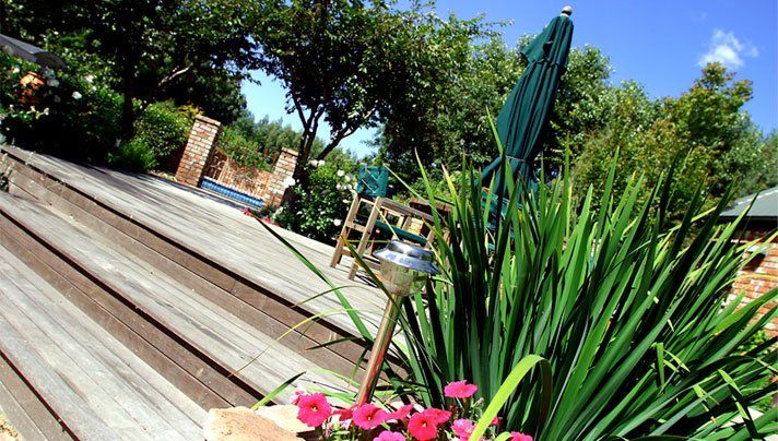 A planter with pink flowers sits on a wooden deck