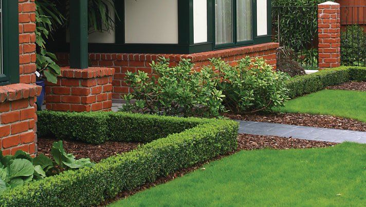 A brick house with a lush green lawn in front of it