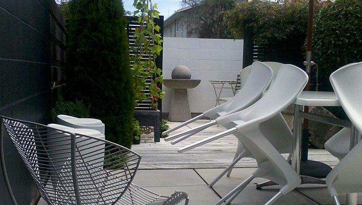 A row of white chairs are lined up on a patio