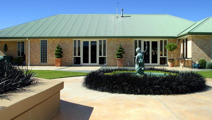 A large house with a green roof and a fountain in front of it