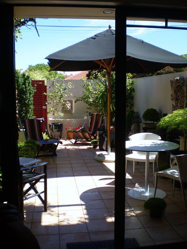 A patio with umbrellas and chairs and a table