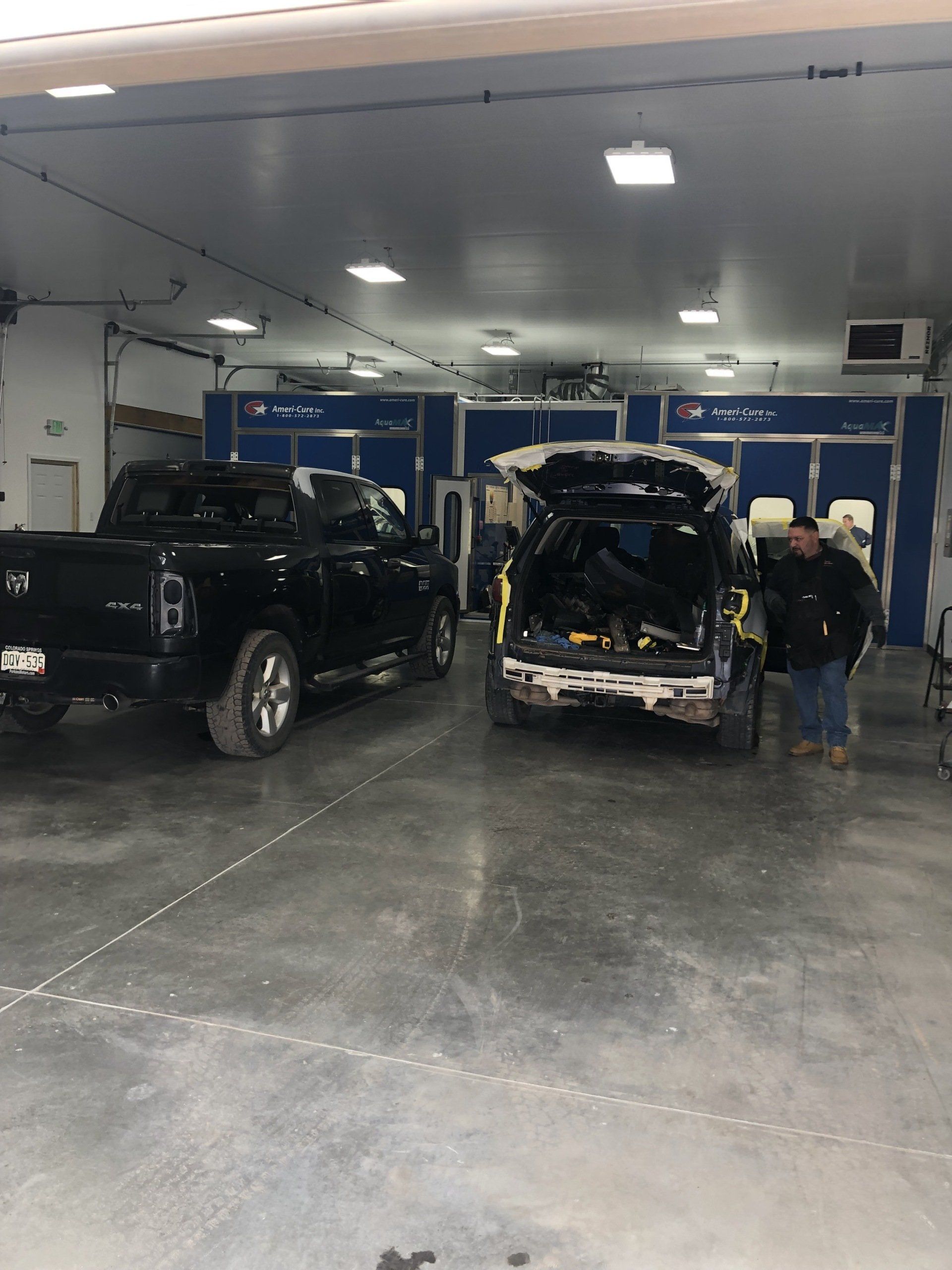 Two trucks are parked in a garage with the trunk open