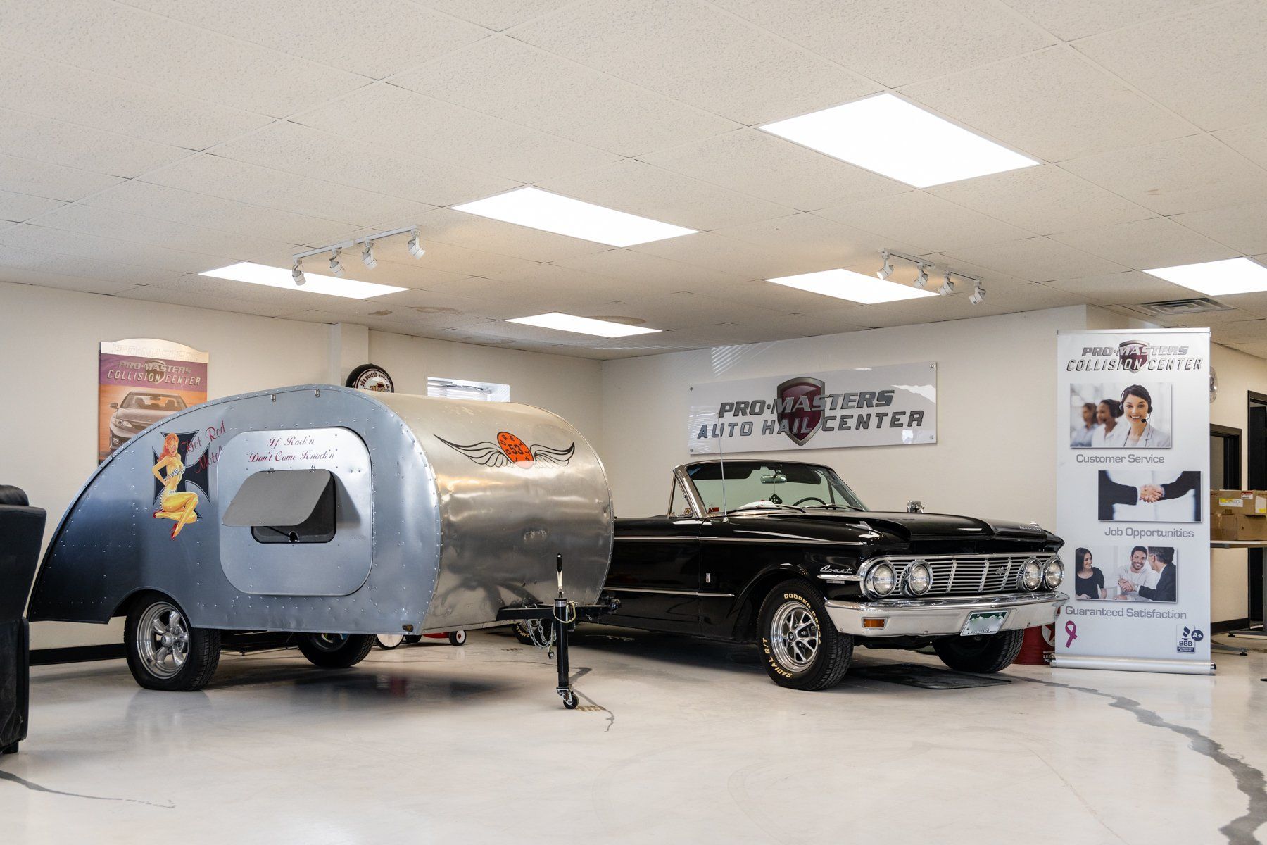 A car is parked in a garage next to a trailer.