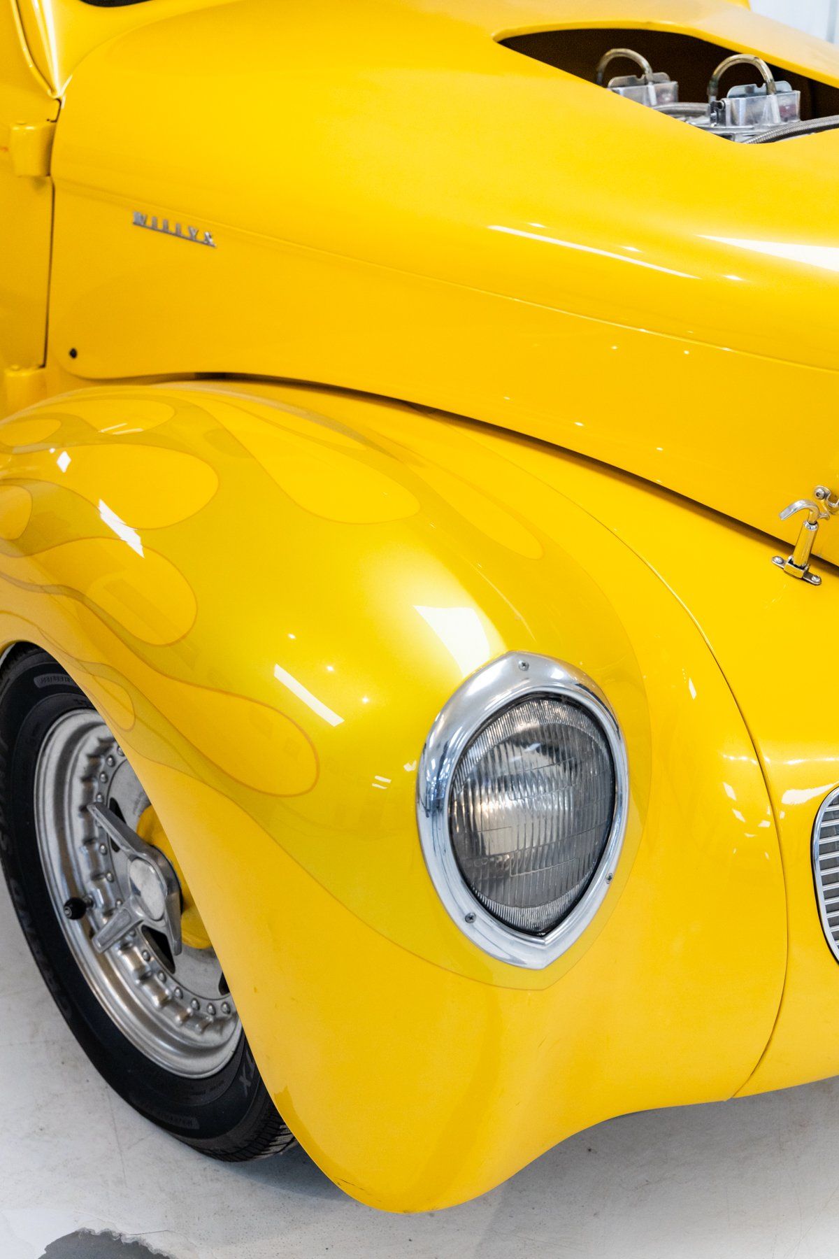 A yellow car is parked in a garage with the hood open.
