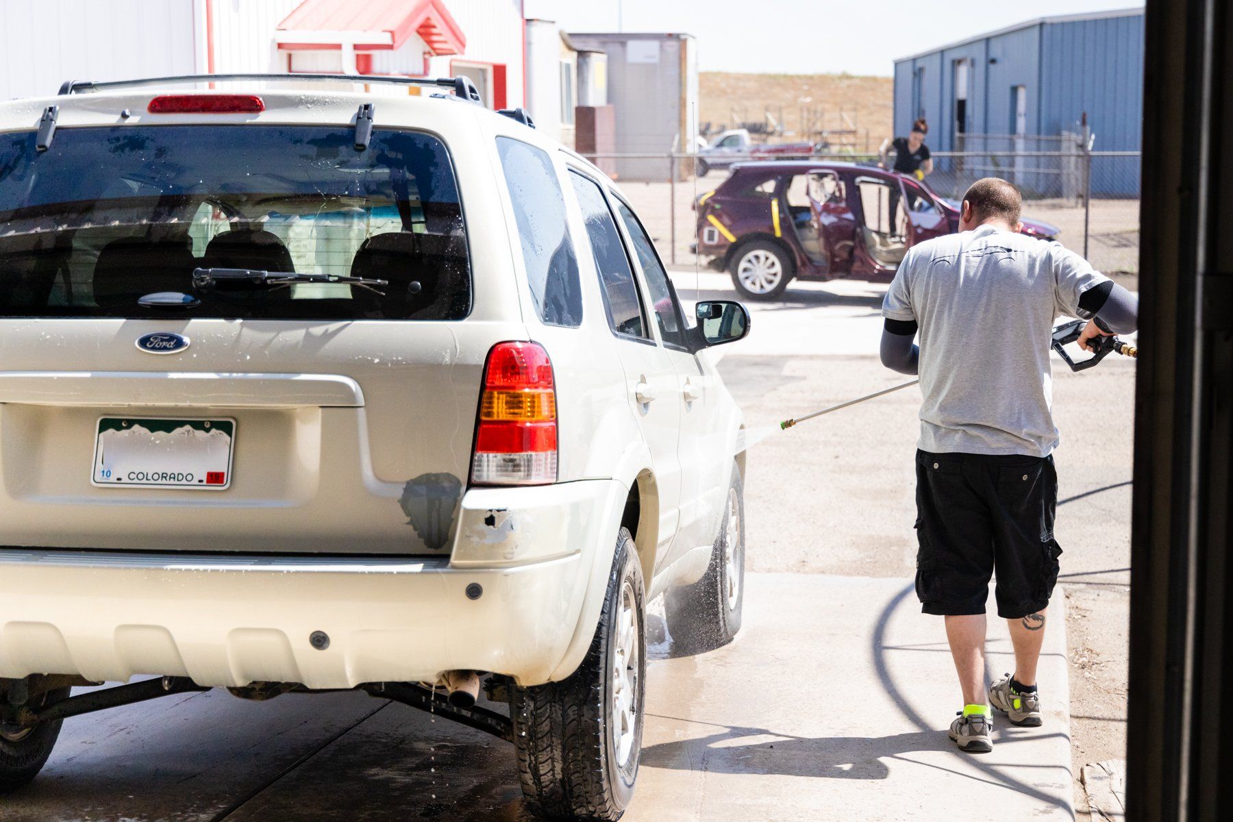 A man is washing a ford escape in a car wash