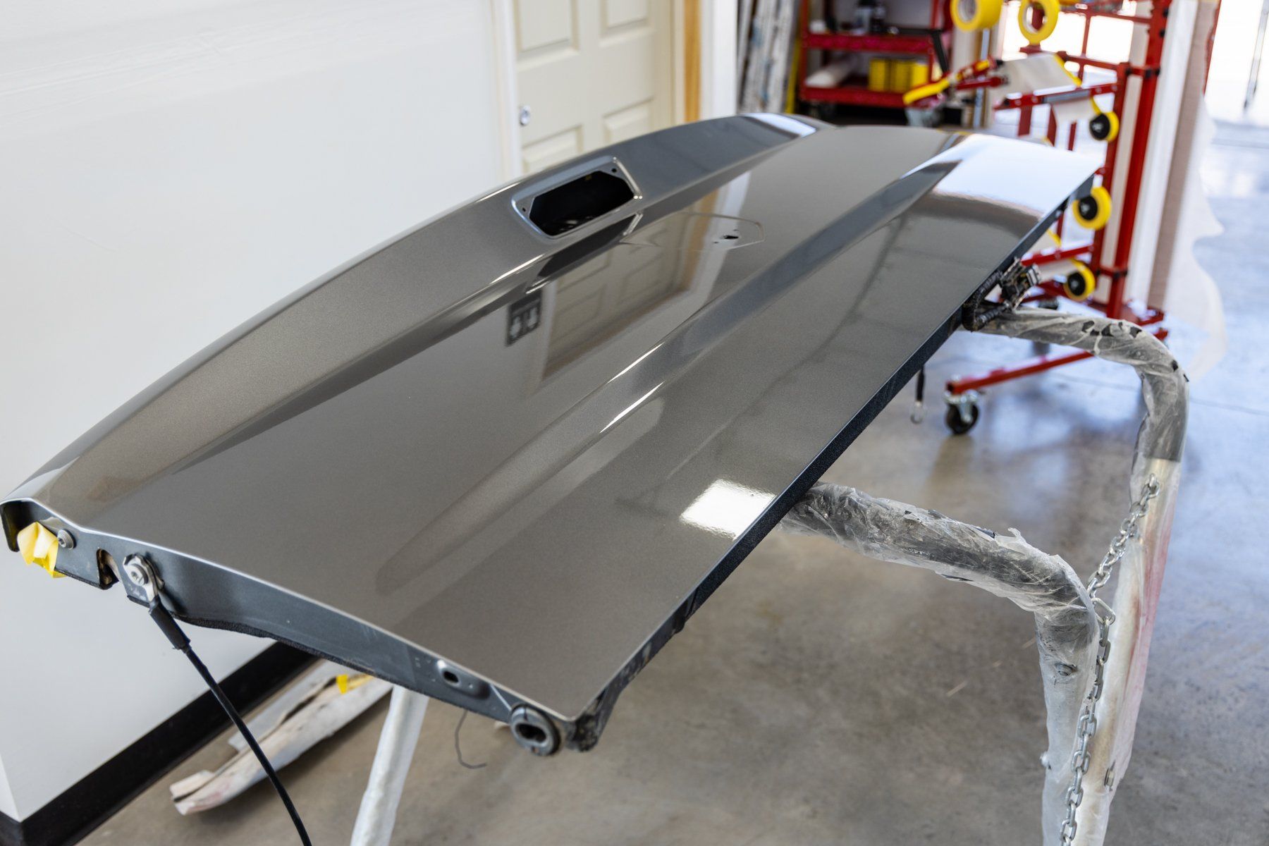 A car door is sitting on a table in a garage.