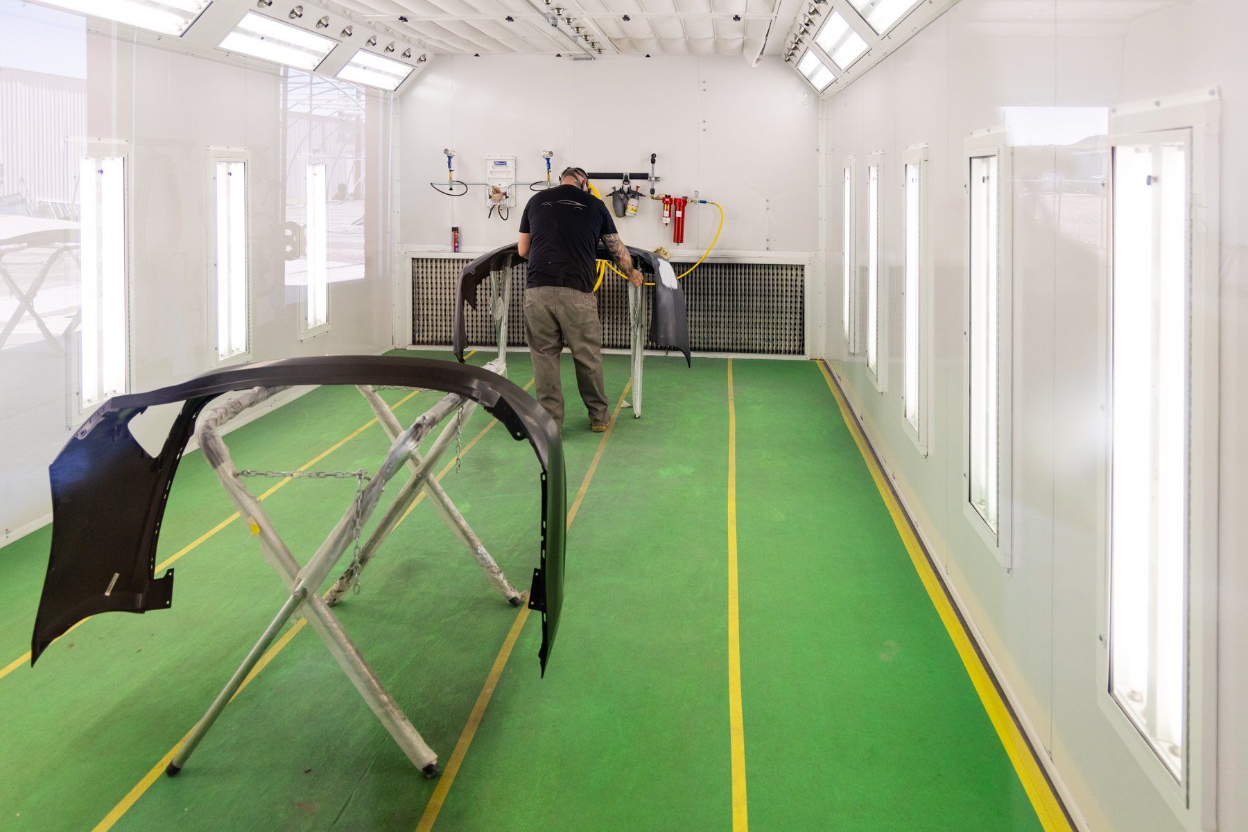 A man is working on a car in a paint booth.