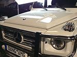 a white mercedes benz g class is parked in a garage .
