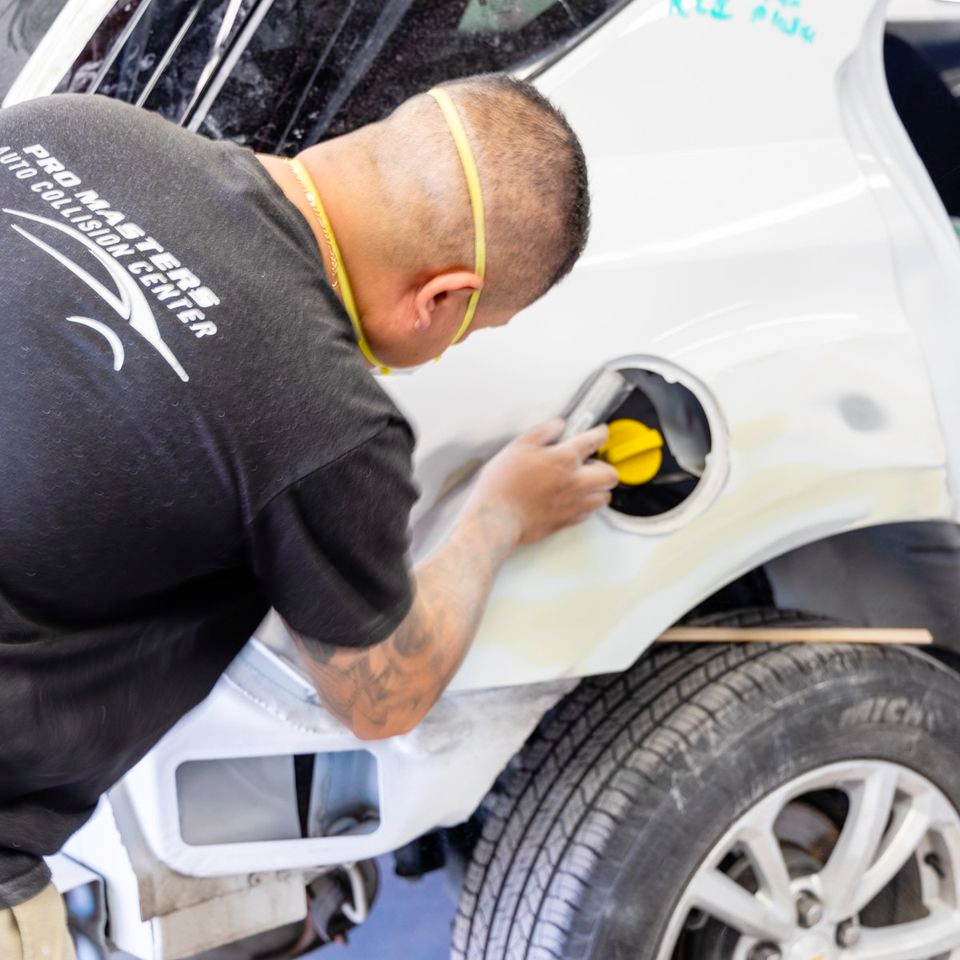 A man wearing a pro masters shirt works on a car