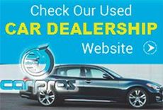 a car is parked in front of a blue sign that says `` check our used car dealership website '' .