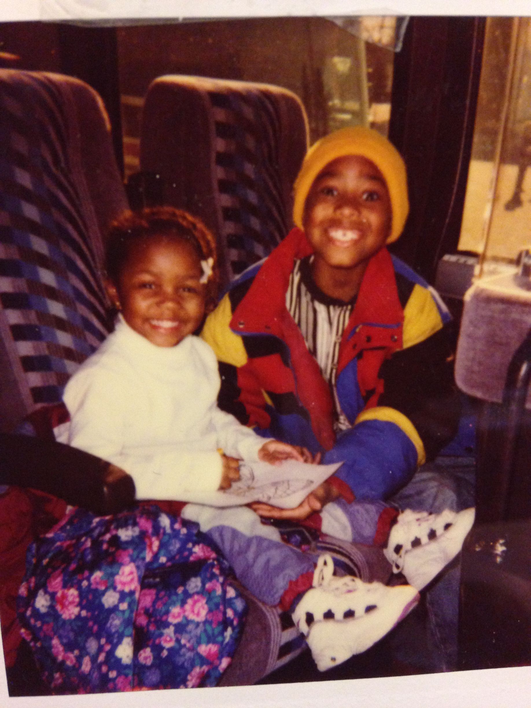A boy and a girl are sitting on a bus and smiling