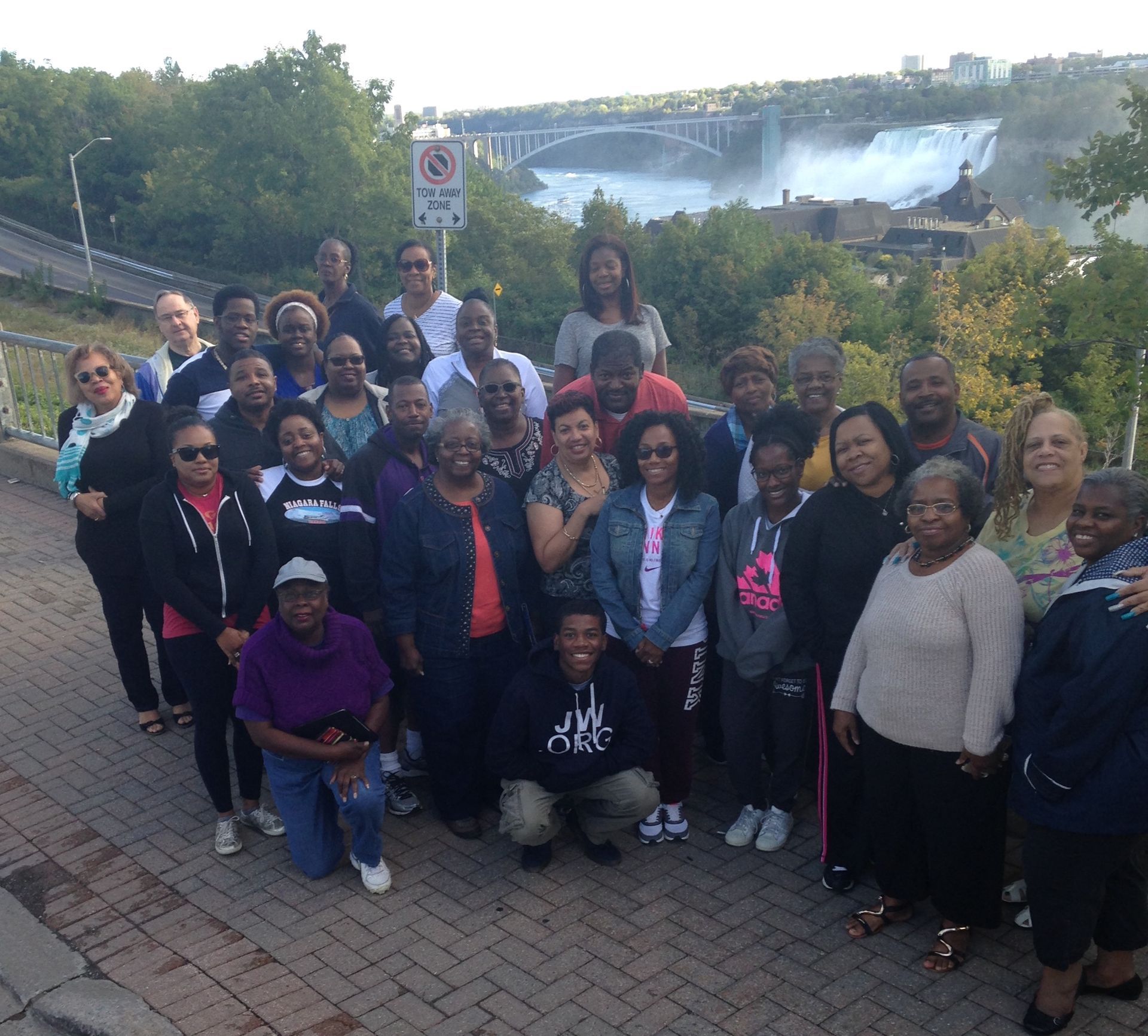 A group of people posing for a picture in front of a no parking sign