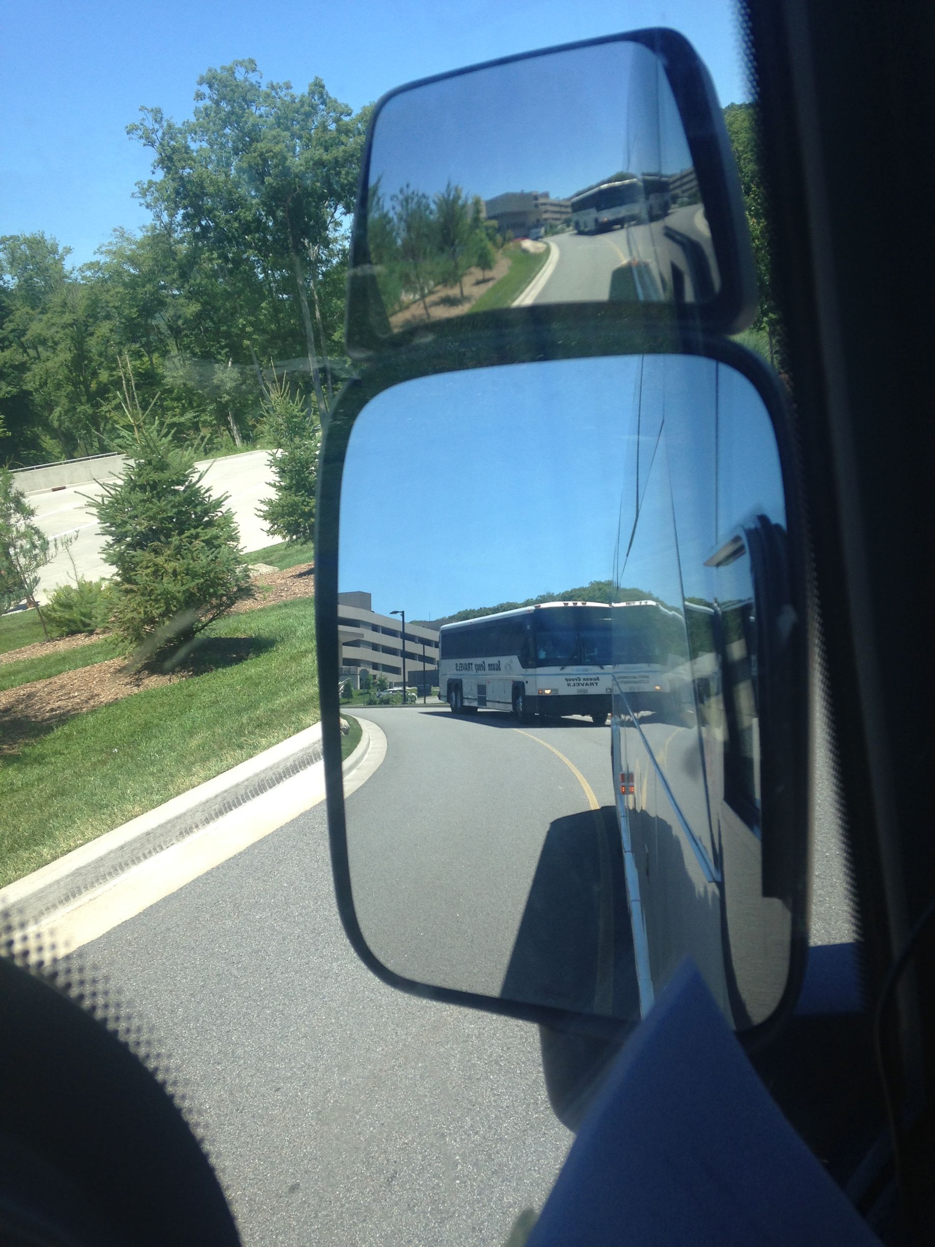 A bus is reflected in the side mirror of a car