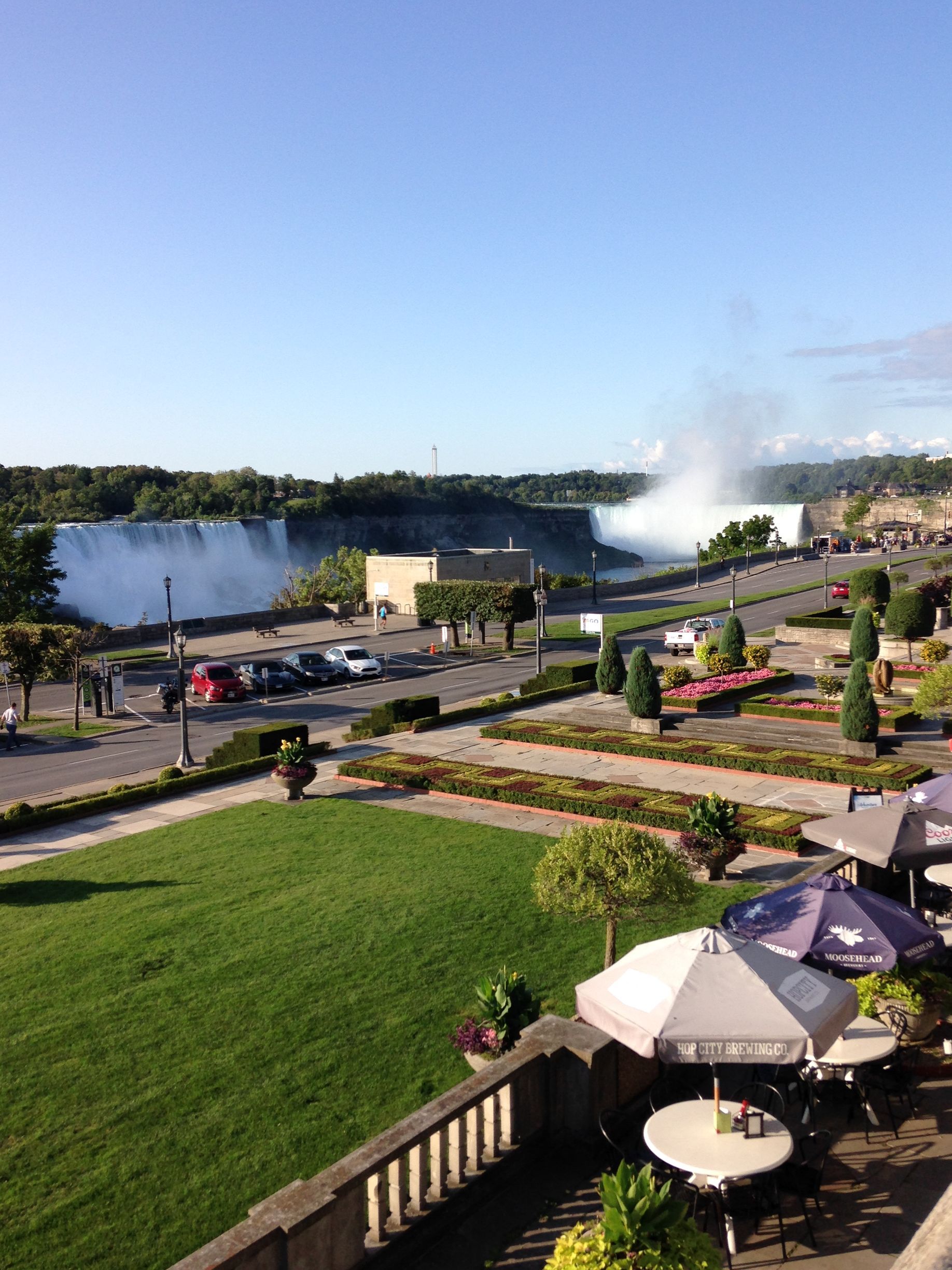 A view of a waterfall from a balcony with tables and umbrellas