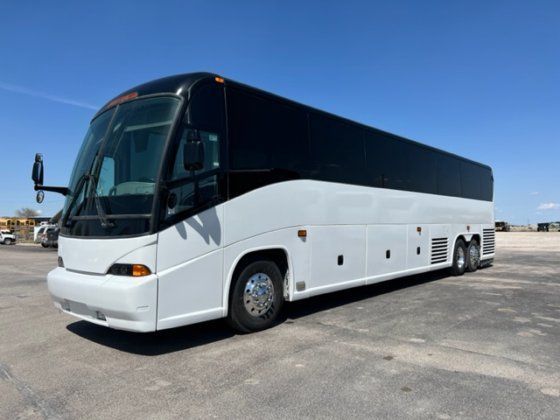 A white and black bus is parked in a parking lot