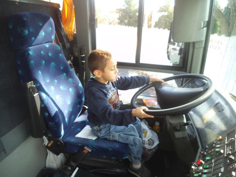 A young boy is sitting in the driver 's seat of a bus