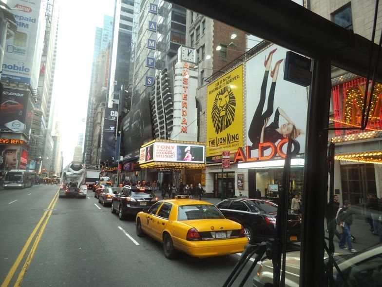 A yellow taxi is driving down a busy city street