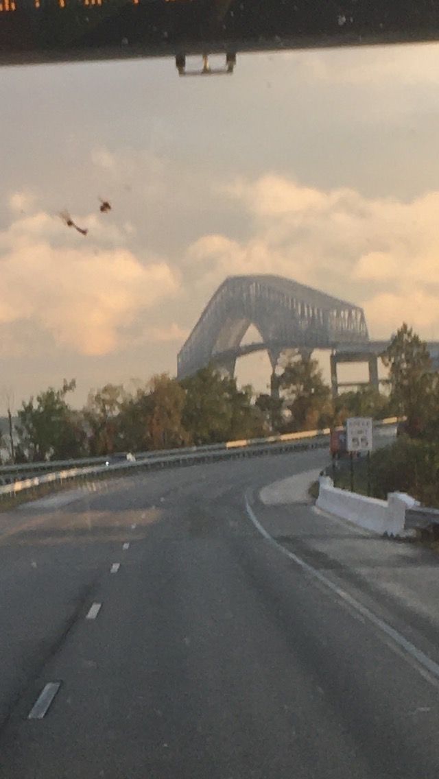 A car is driving down a highway with a bridge in the background
