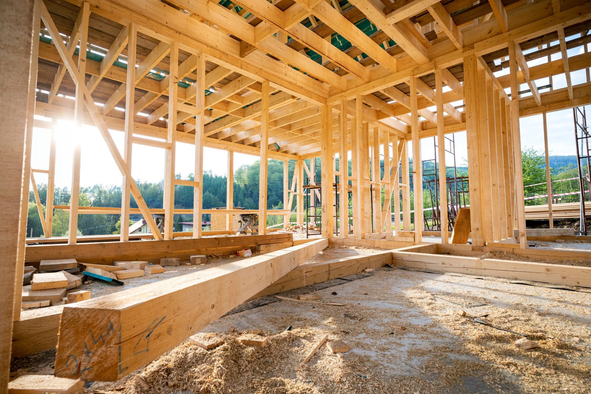 The sun is shining through the windows of a wooden house under construction.