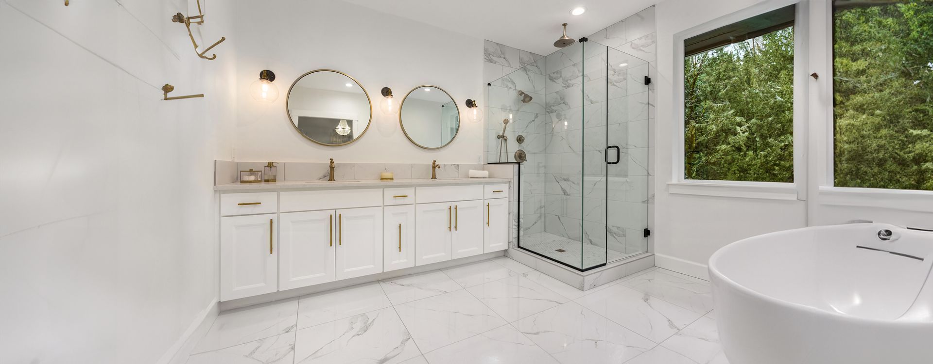 Modern white bathroom with double vanity, walk-in shower, and freestanding tub.
