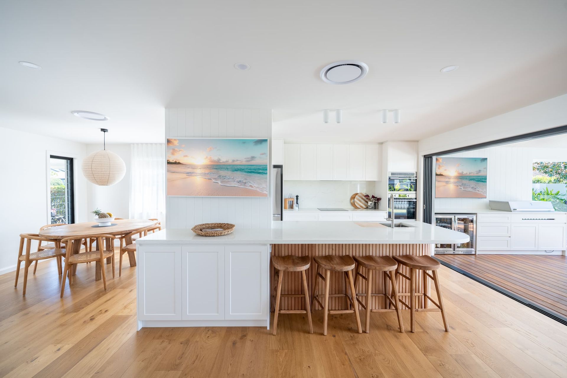 Open-concept kitchen with white cabinetry, wooden accents, and a large island with bar stools.