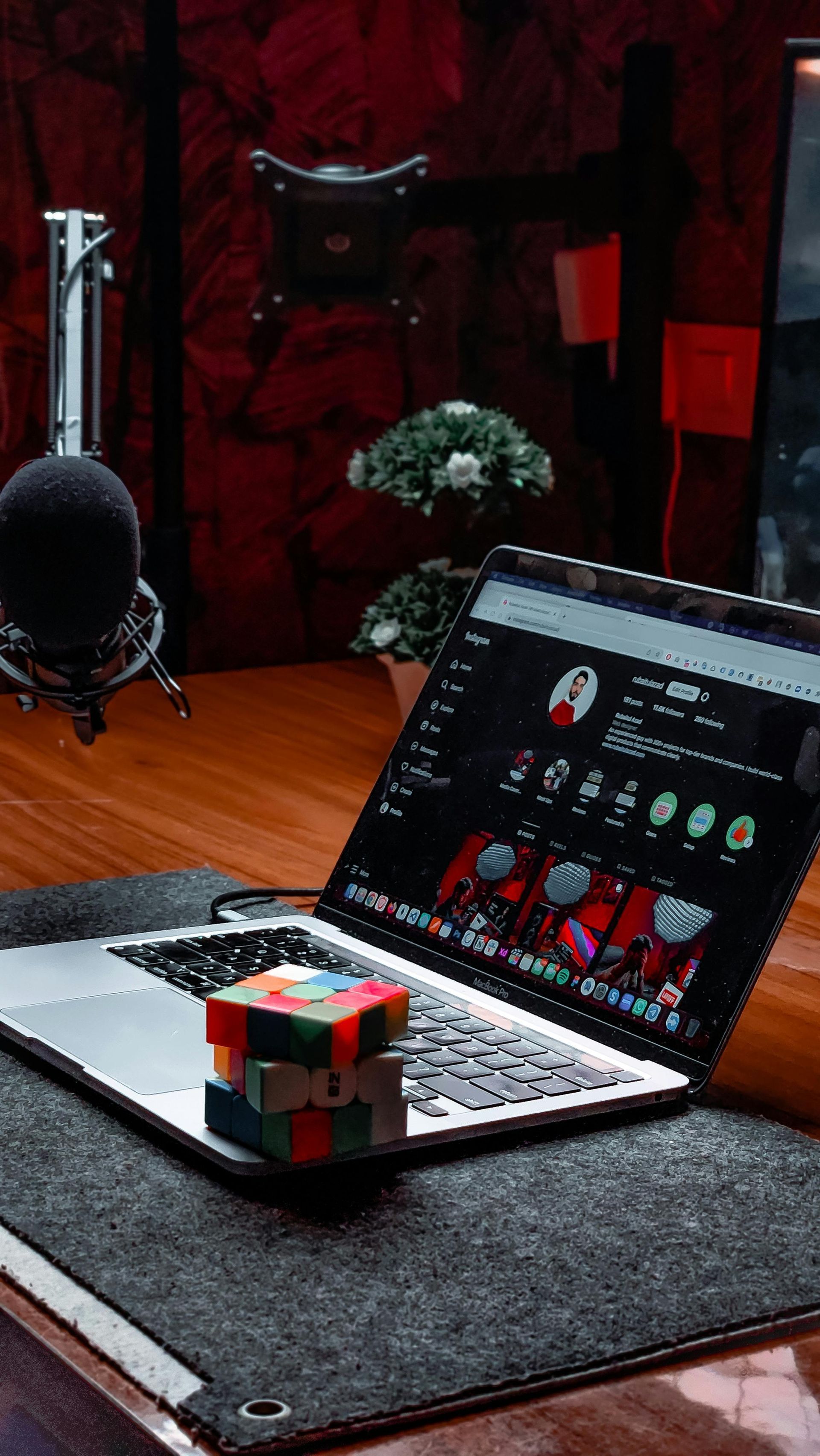 Laptop on a desk with a colorful cube, microphone, and dark studio lighting