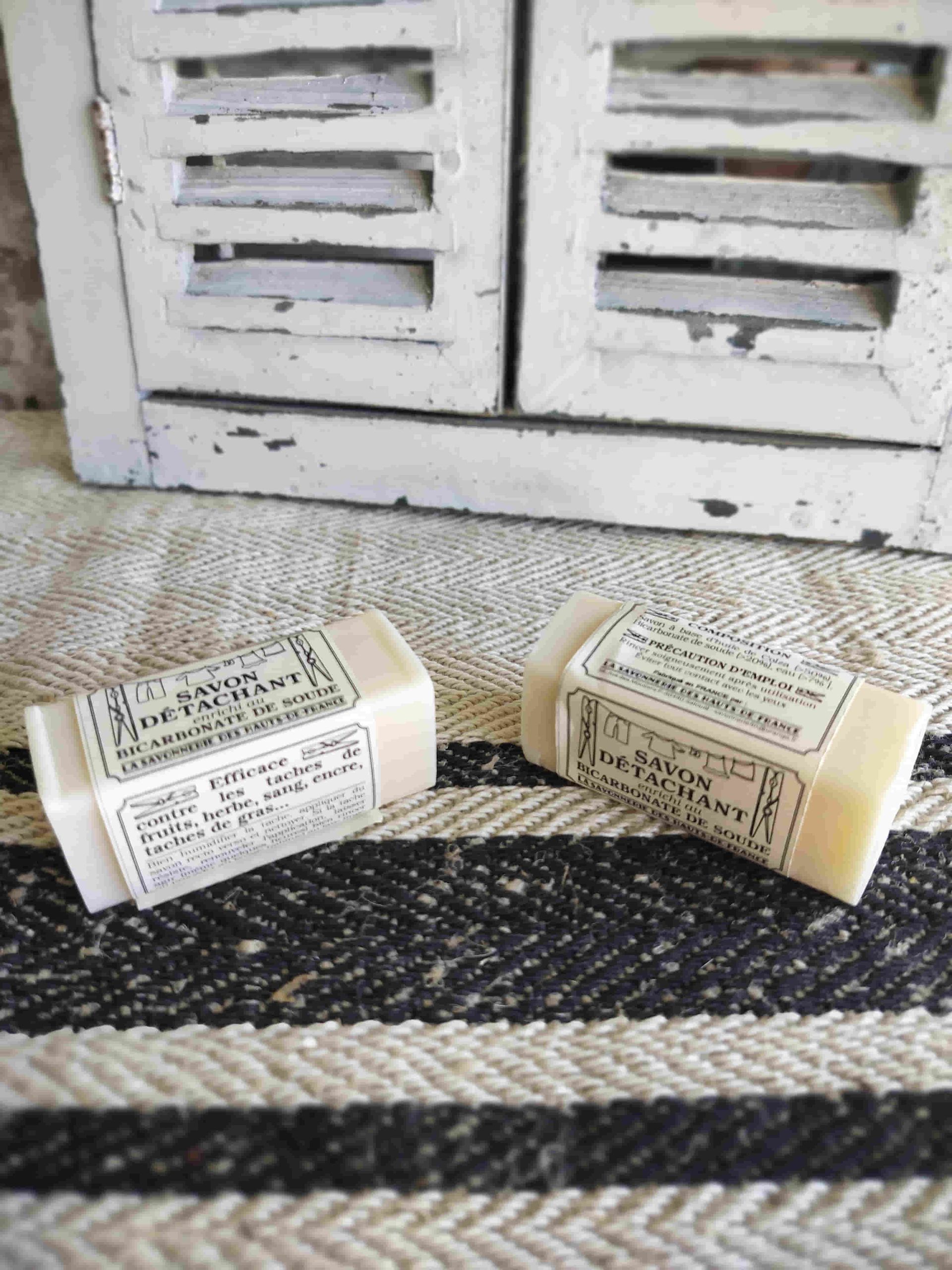 Two bars of soap are sitting on a rug in front of a window.