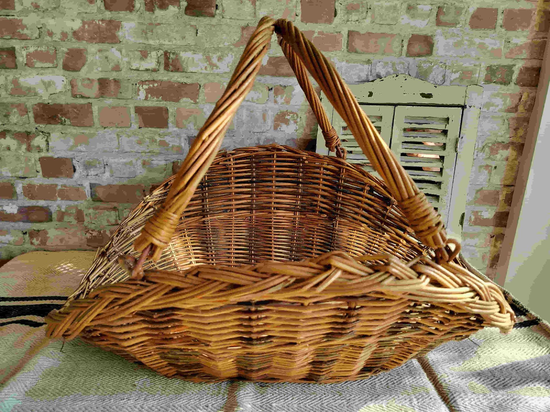 A wicker basket is sitting on a table in front of a brick wall.