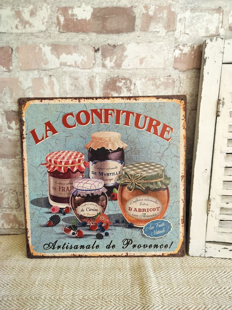 A sign that says la confiture is hanging on a brick wall.