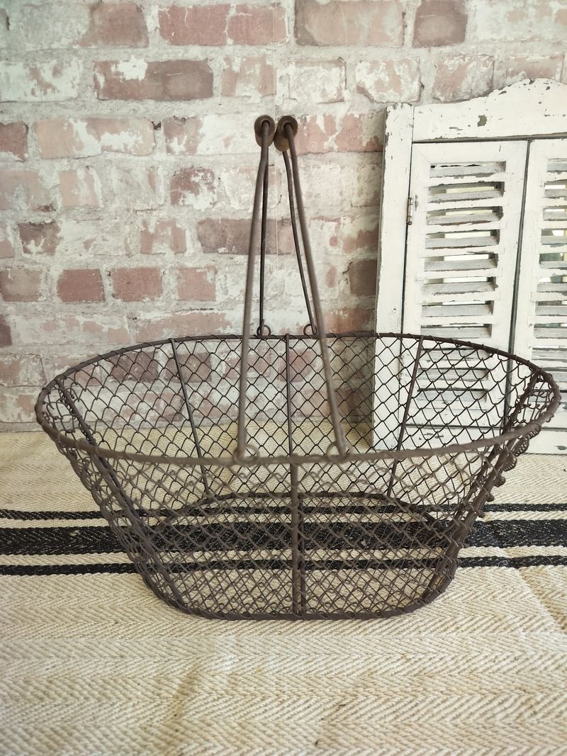 A wire basket is sitting on a rug in front of a brick wall.