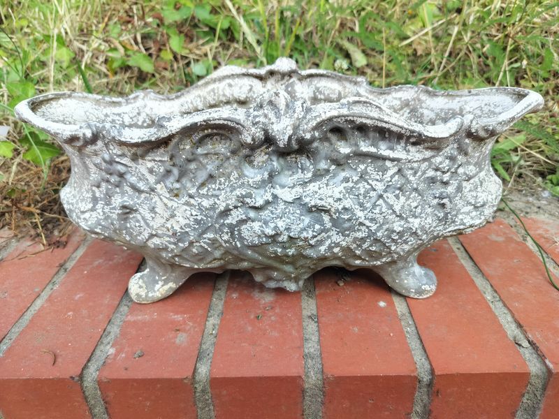 A silver vase is sitting on a brick wall