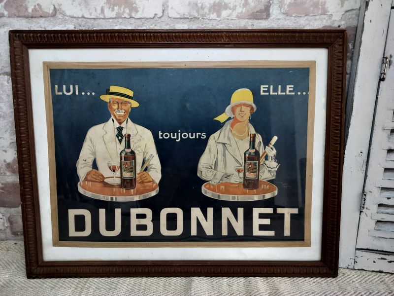 A framed picture of a man and woman holding bottles of dubonnet