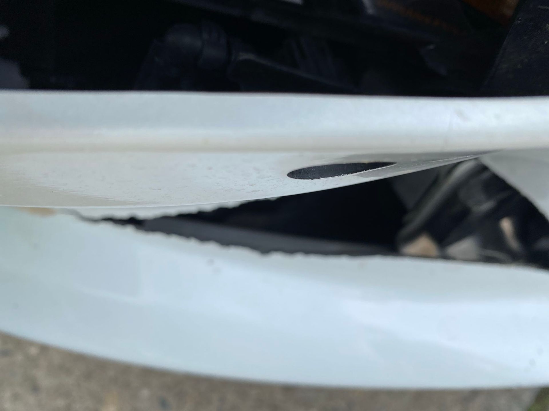 White car bumper with a large crack along its edge.