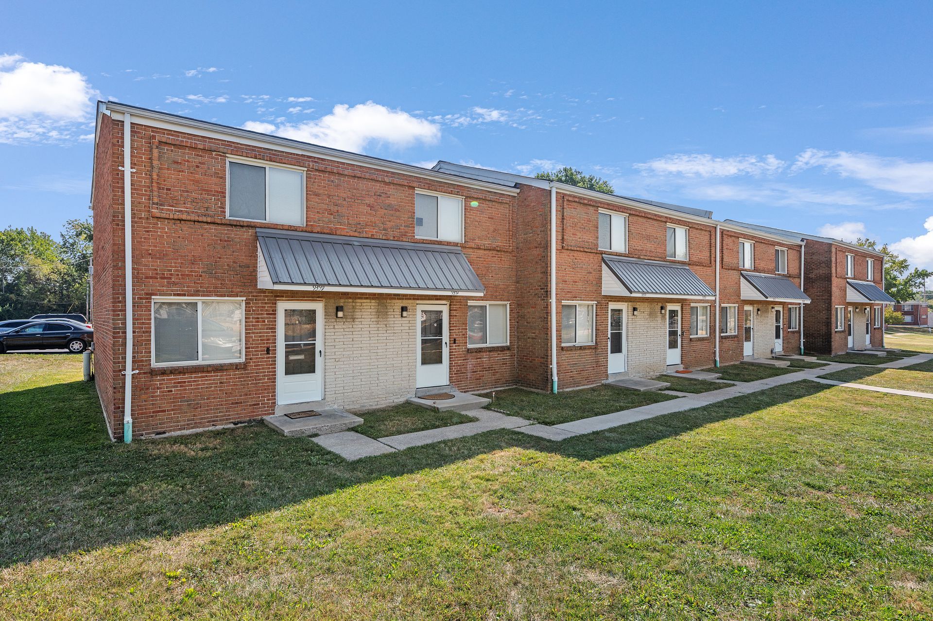 A row of brick apartment buildings sitting next to each other on a lush green field.